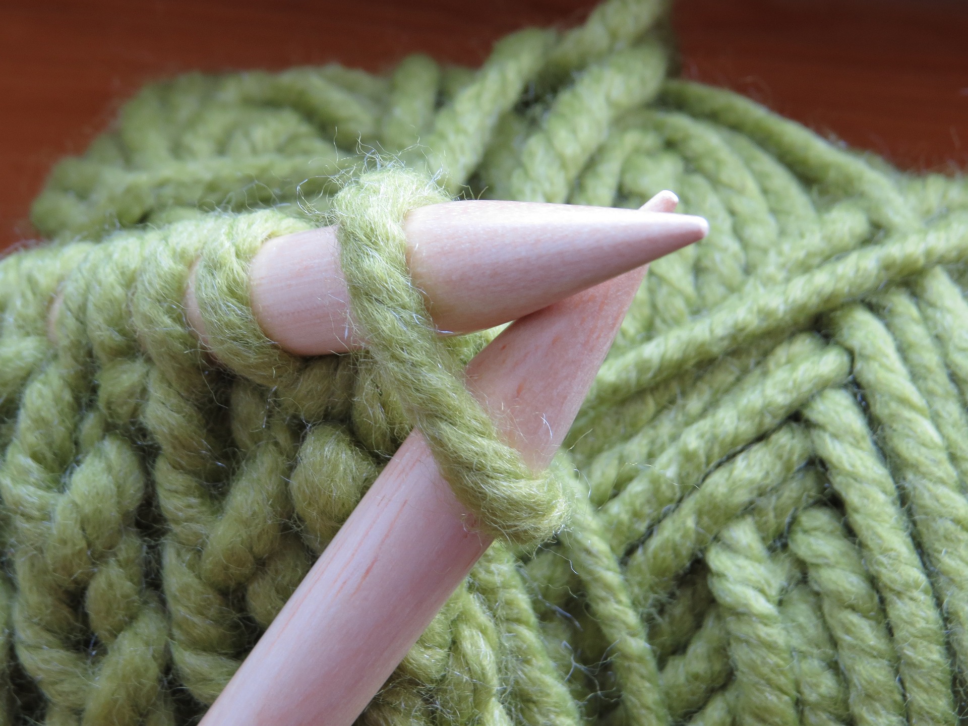 wooden knitting needles and green yarn