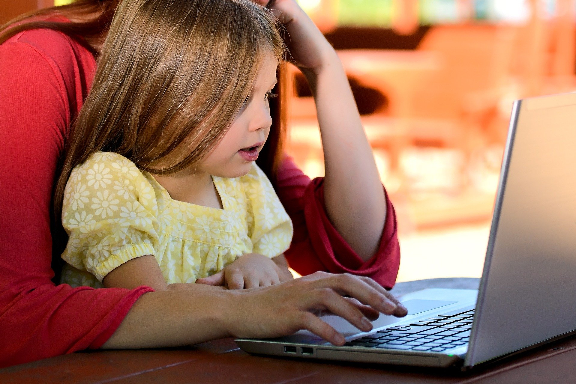 parent and child sit together in front of a laptop screen