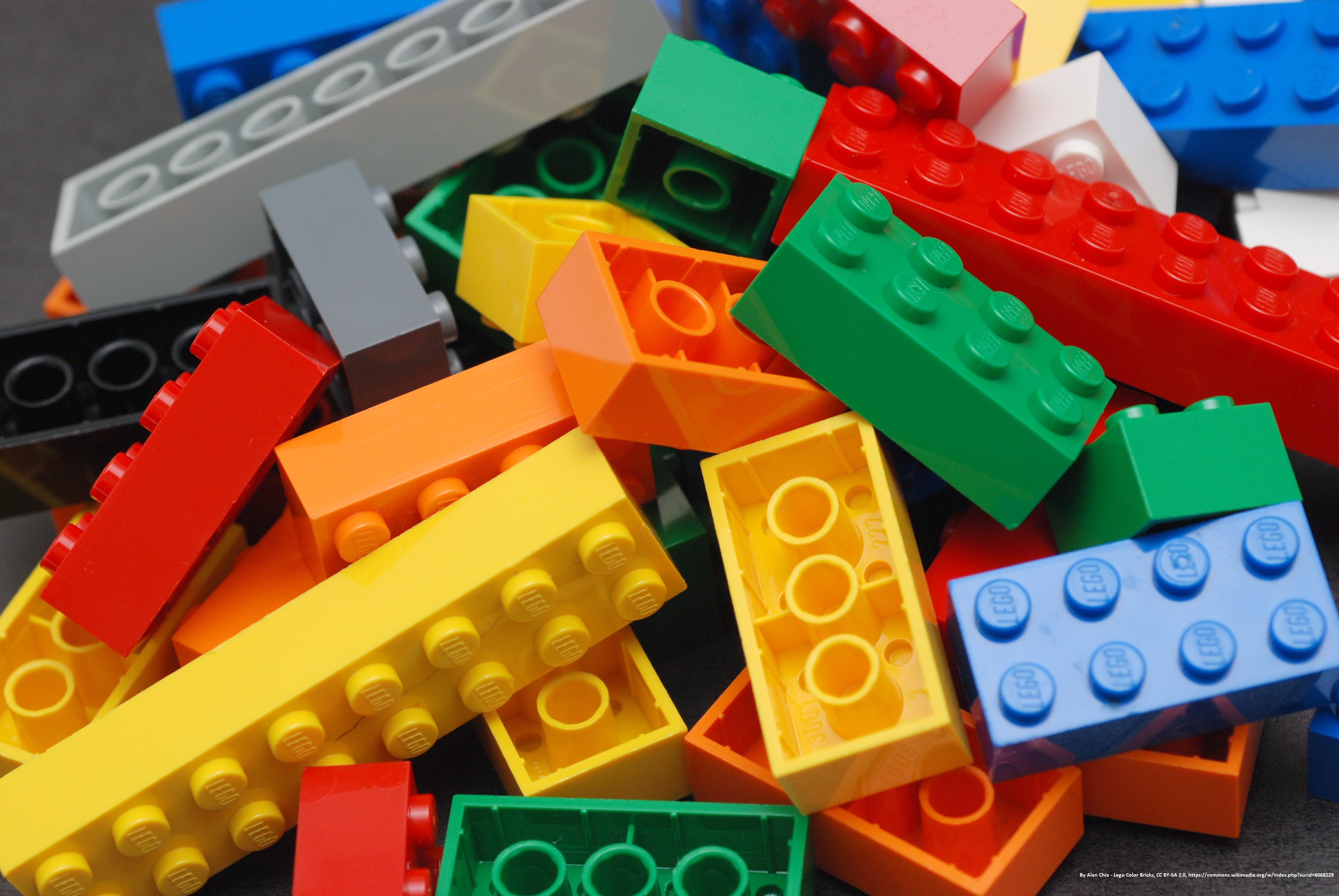 Pile of multicolored LEGO bricks on a dark gray background