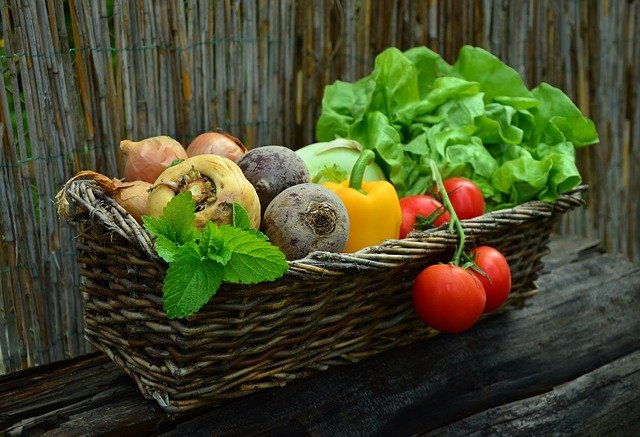 basket of assorted colorful vegetables on a wooden table 