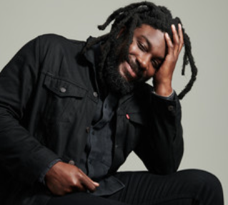 photograph of Jason reynolds smiling, resting his head on his hand