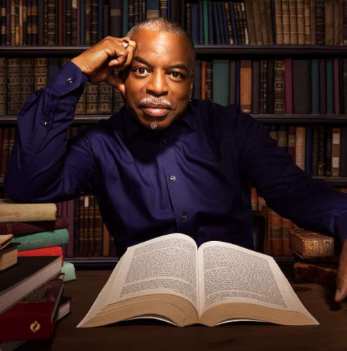 photo of levar burton with a book open on the table in front of him