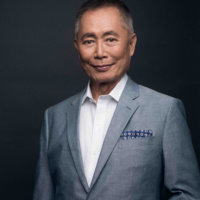 photo of george takei in a gray suit white shirt with black background