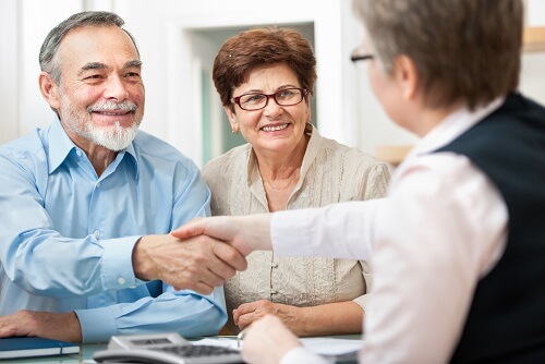 an attorney shakes hands with an older smiling couple