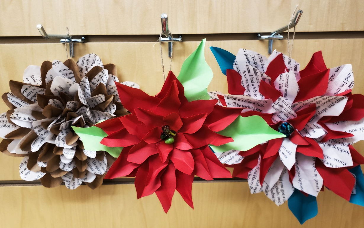 three hanging paper flowers made with colored paper and recycled book pages