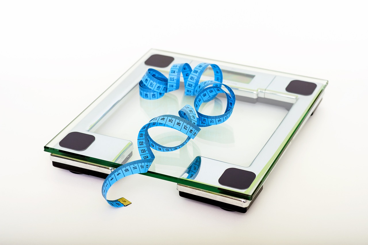 a clear glass scale with a blue measuring tape coiled on top
