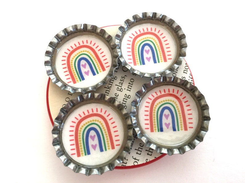 Four bottle cap magnets with rainbows in the center