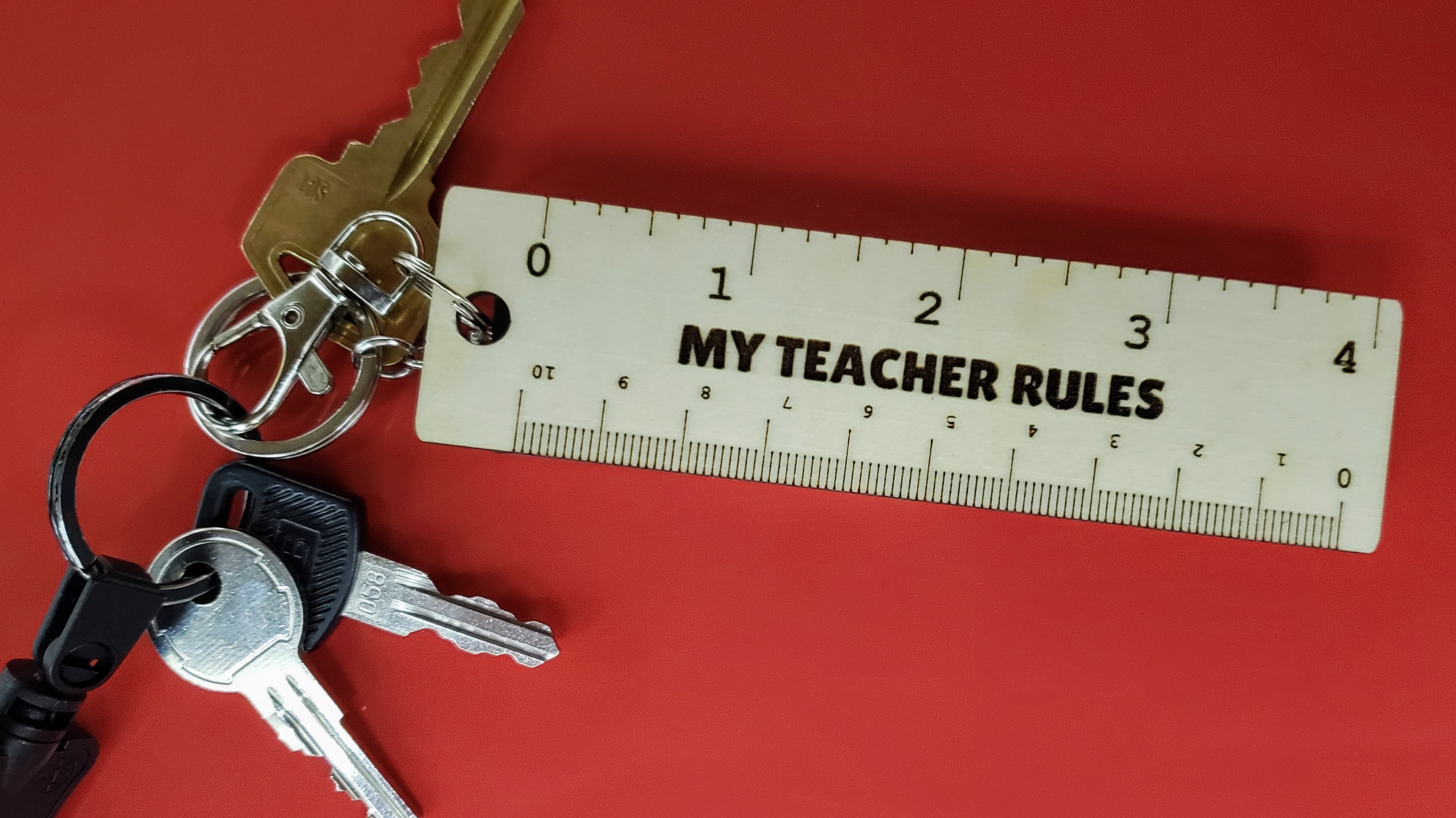 Wooden Keychain Ruler with text My Teacher Rules on a red background