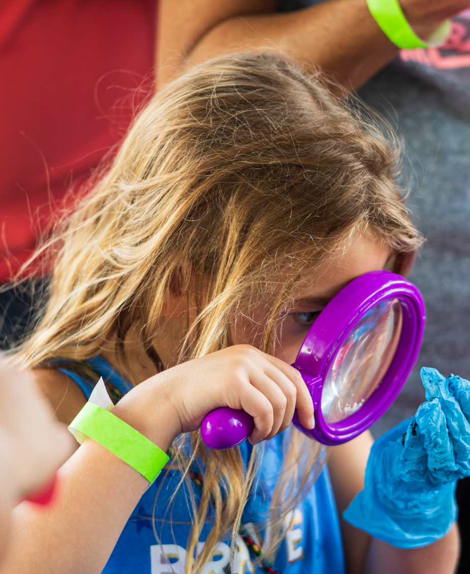 A child looking through a purple magnifying glass