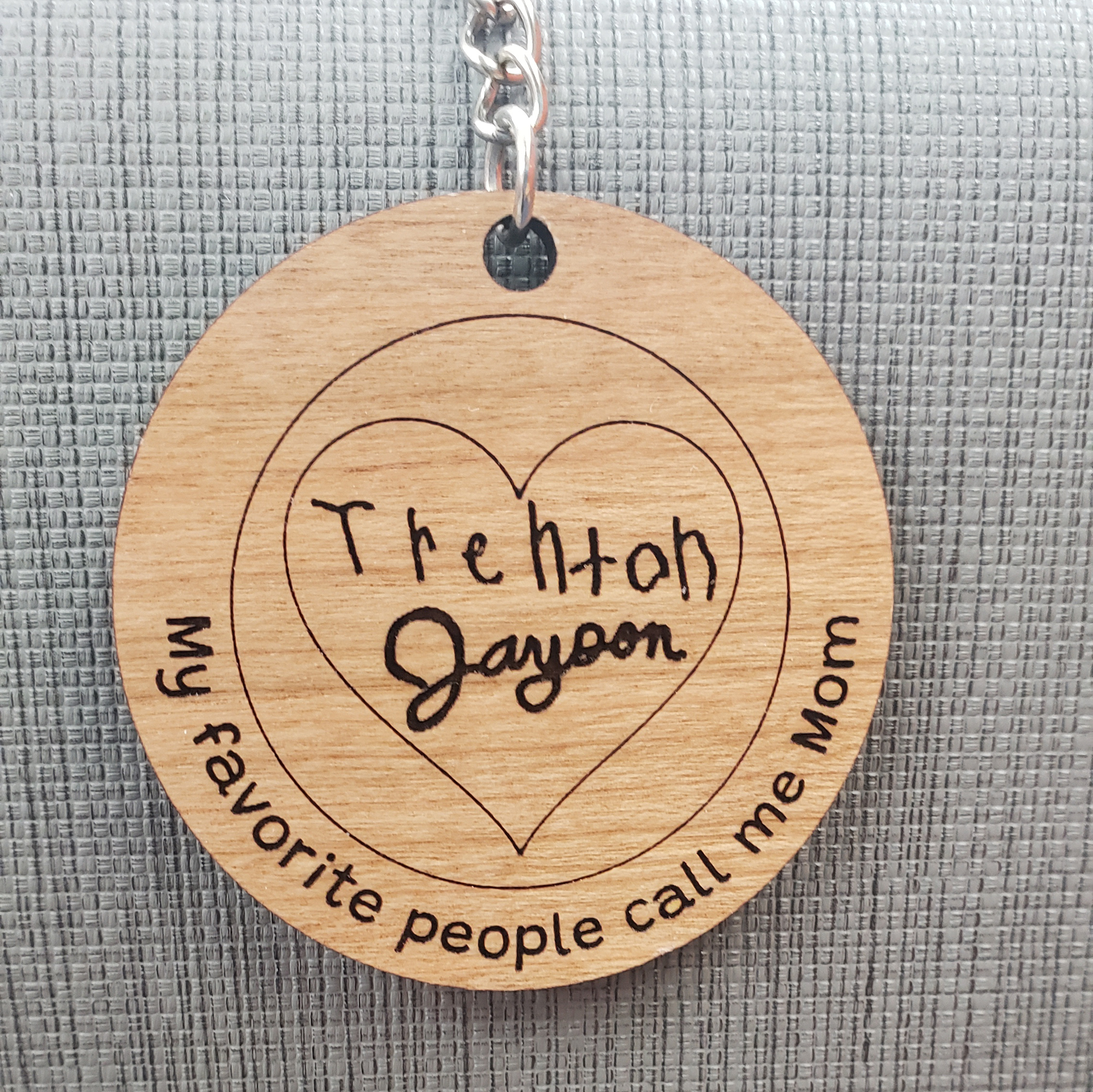 circular engraved wooden keychain with 2 signatures that reads "my favorite people call me mom" and has an engraved heart and circle 