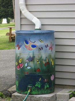 painted rain barrel sitting next to house