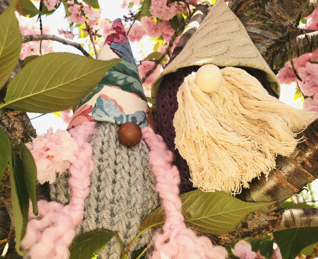two gnomes crafted from socks in pointed fabric hats sitting in a tree