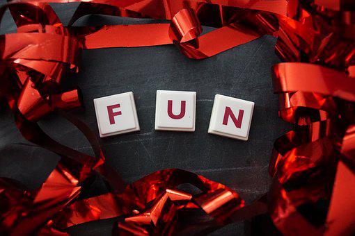 F U N spelled out in letter tiles on black background with red ribbon