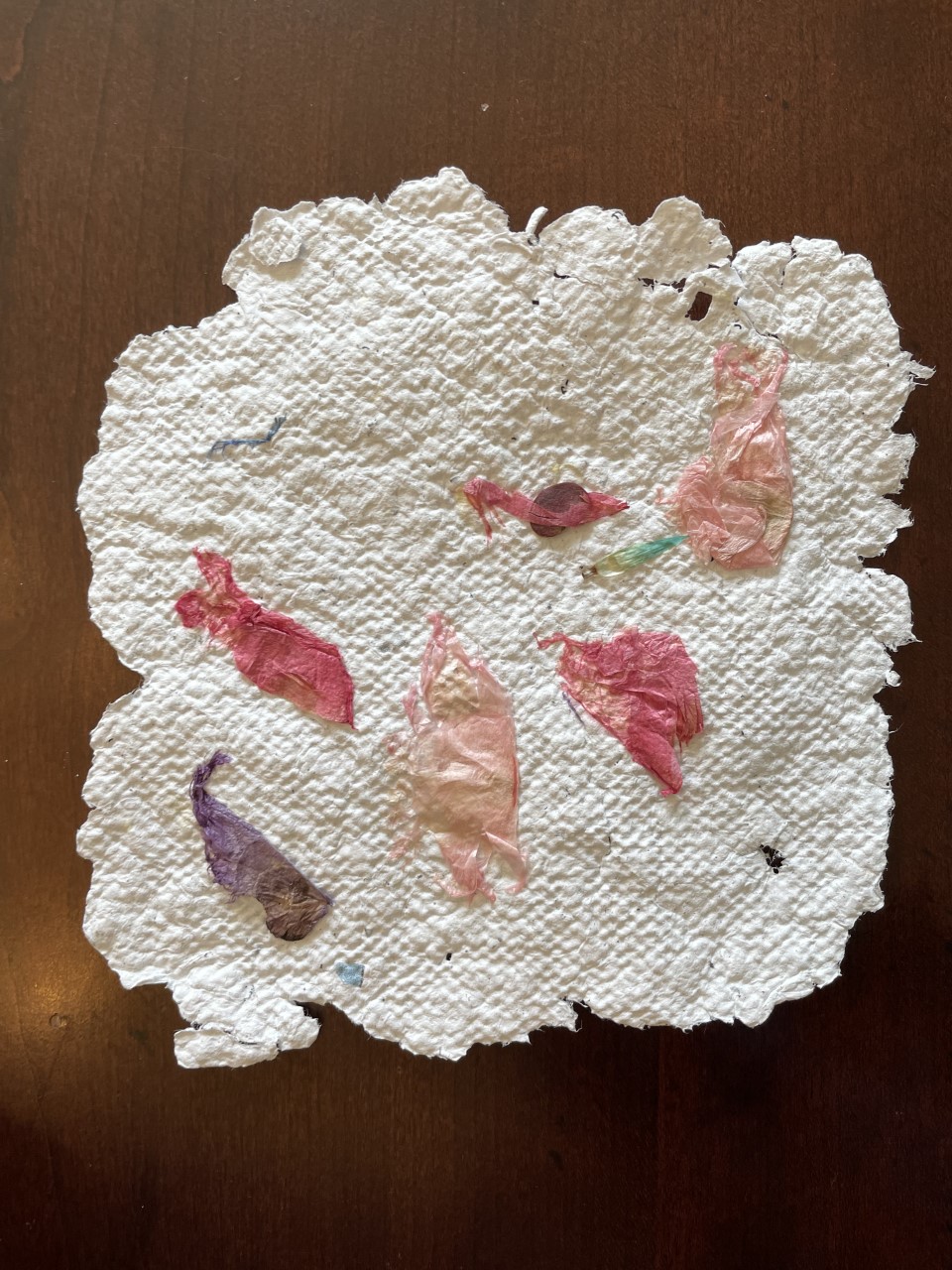 handmade textured paper in irregular shape and scattered with flower petals