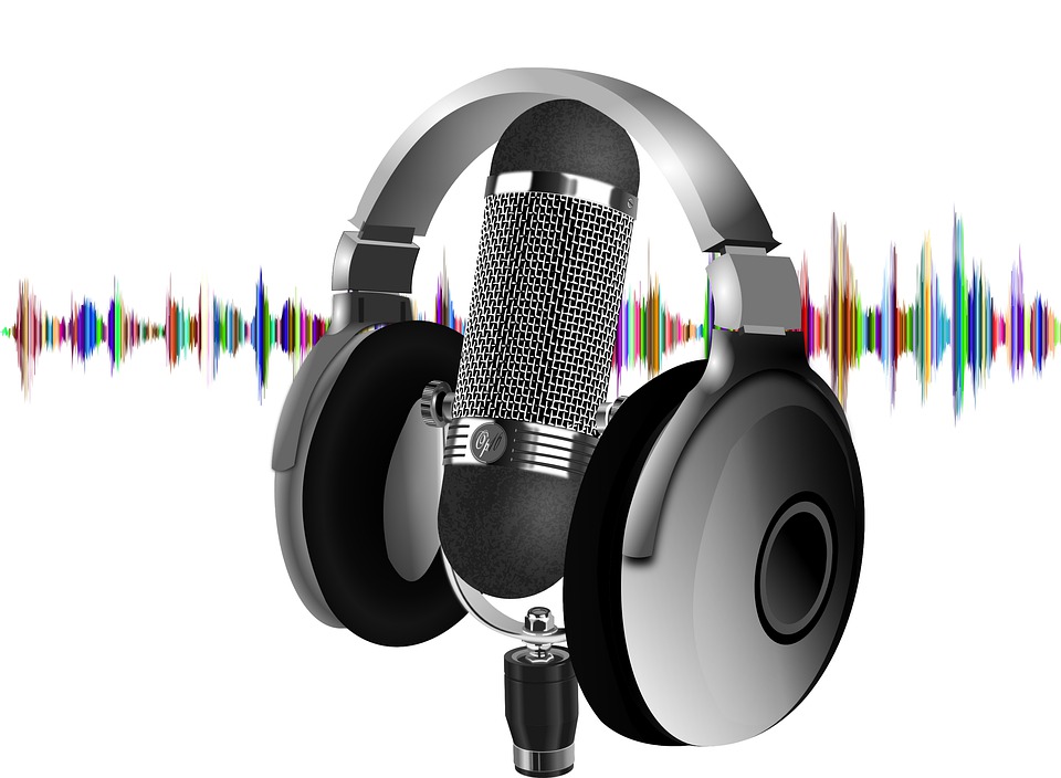 White background with a set of headphones resting on top of a microphone