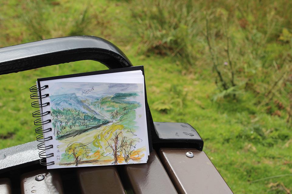 sketchbook outside on bench with outdoor scene drawn in it