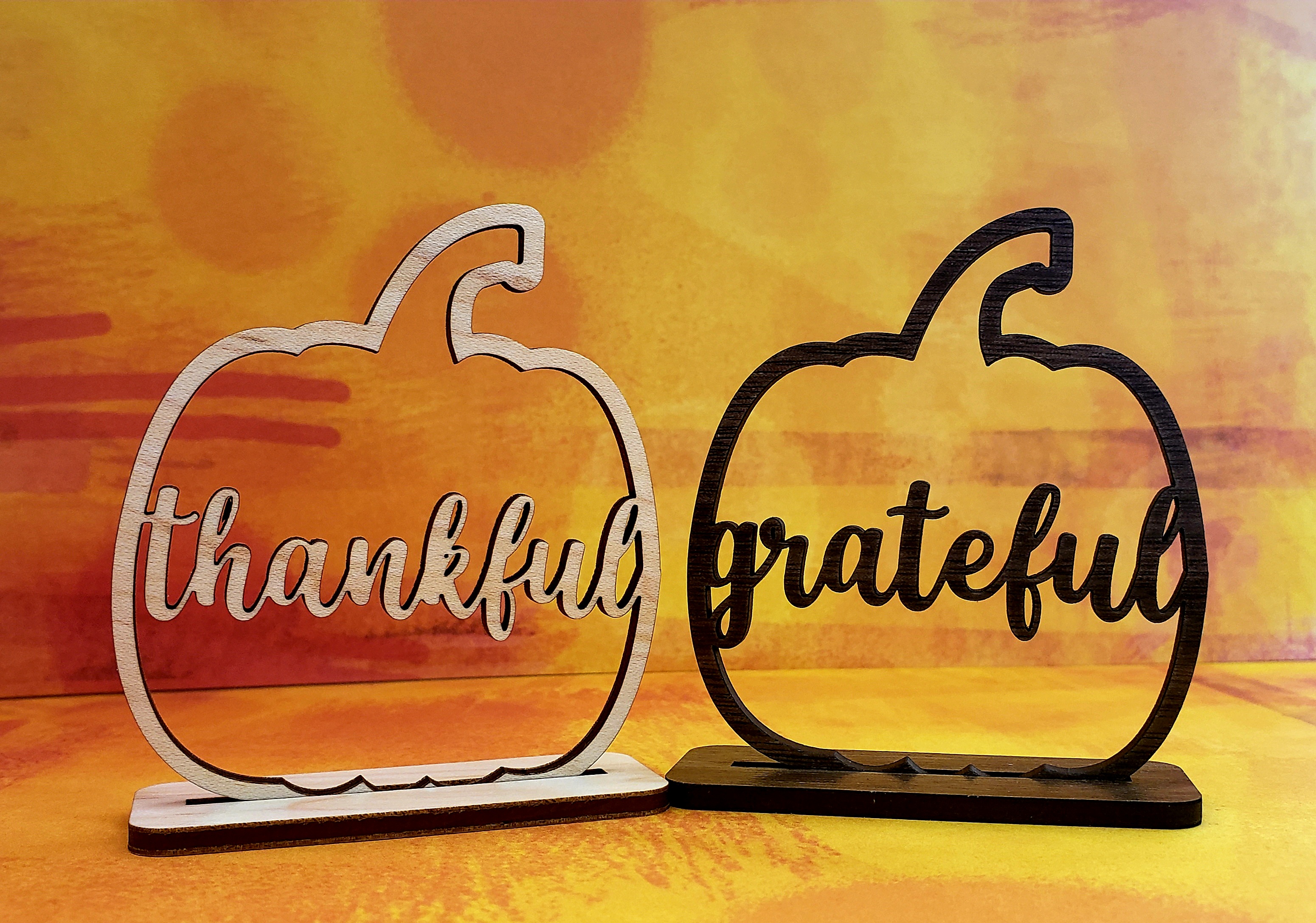 two cut out pumpkins shown - one reads thankful, the other grateful
