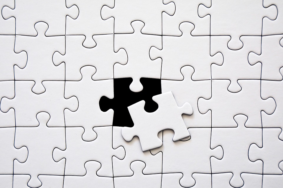 White jigsaw puzzle with missing piece moving into its place
