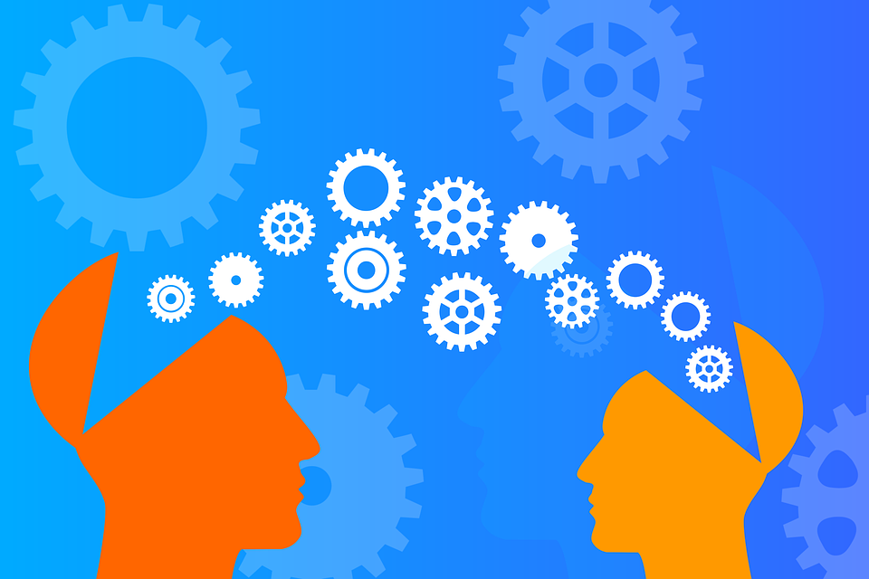 gears moving between 2 orange head outlines indicating sharing knowledge, on blue background