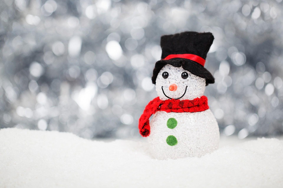 small snowperson with red scarf and black hat with snowy background