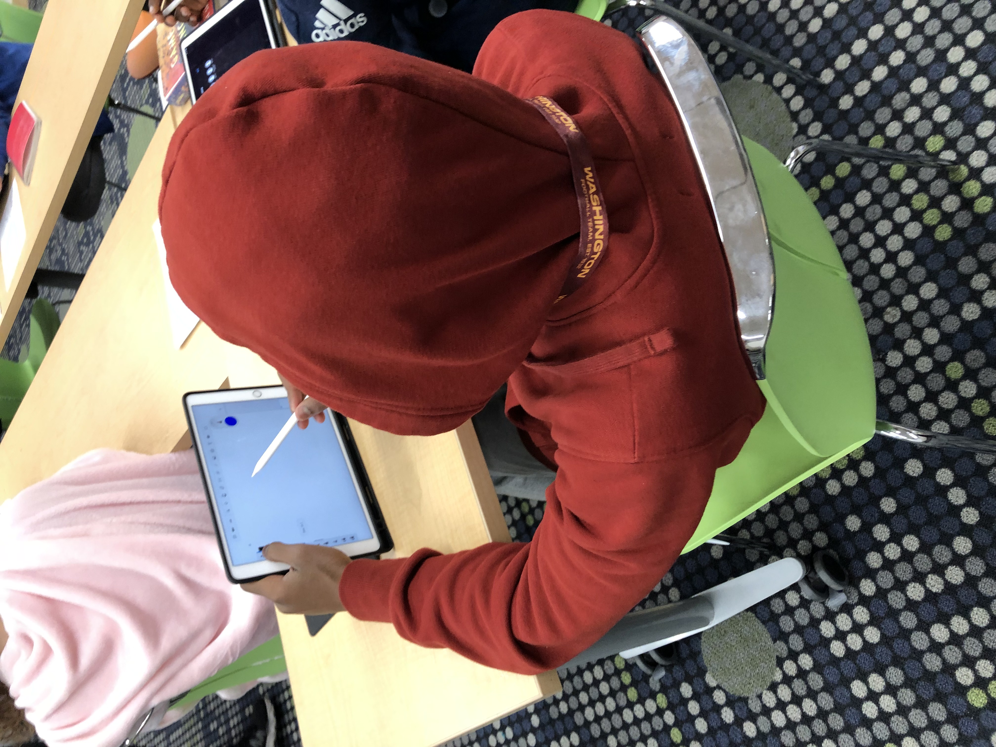 student working on iPad in red hoodie