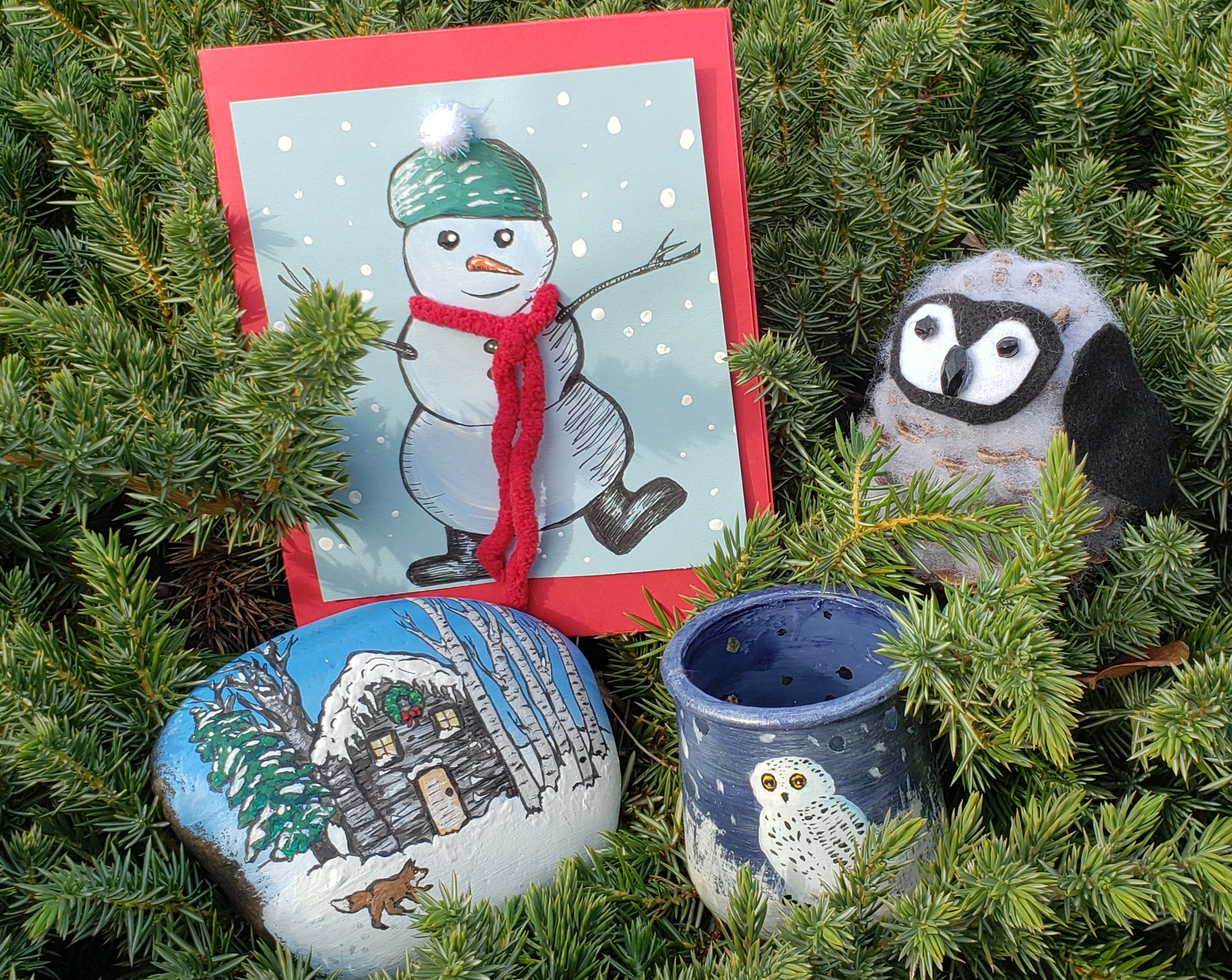 a snowman card, a jar painted with a snowy owl, a rock painted with a winter scene and a pinecone penguin