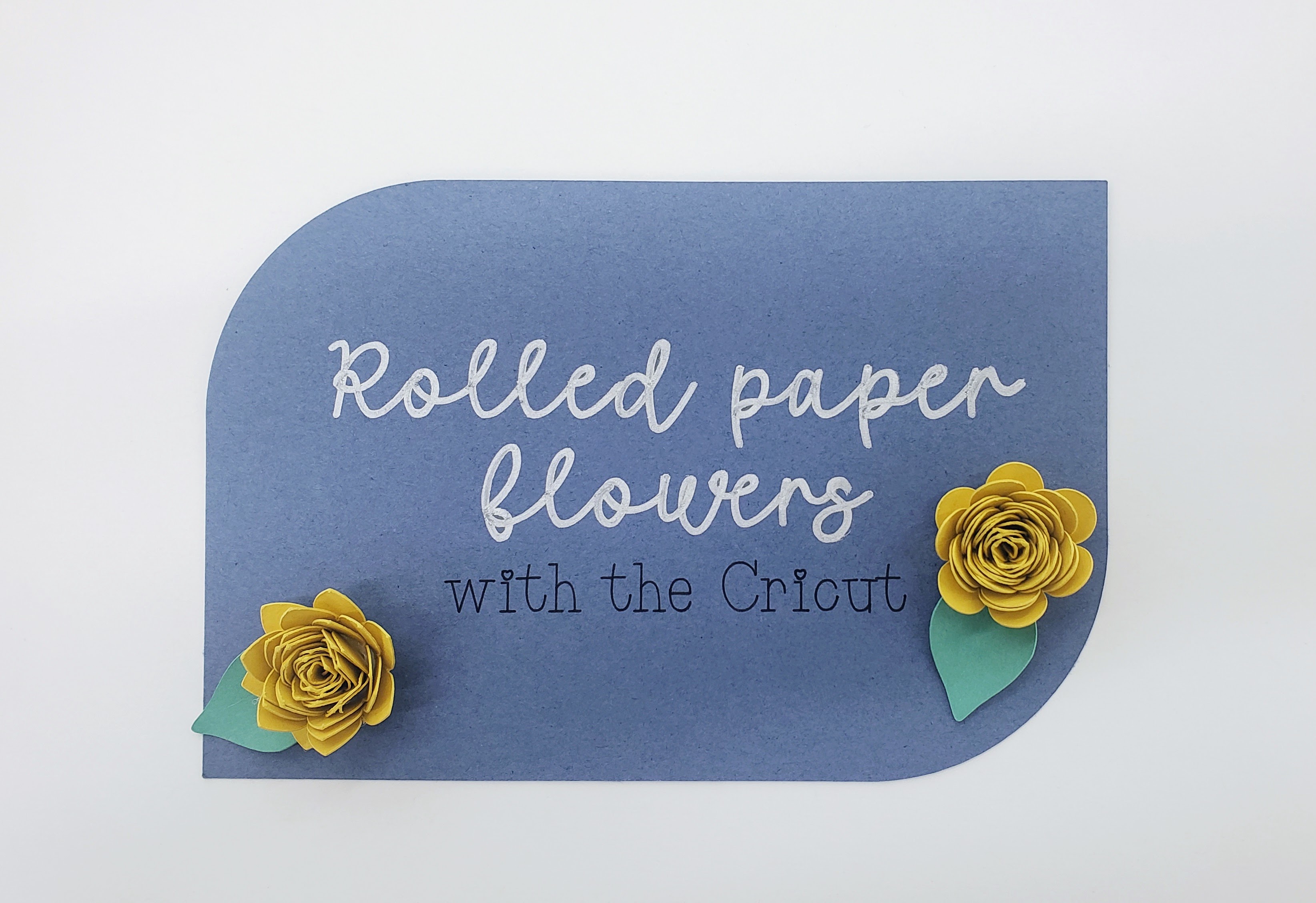 Blue background with yeloow paper flowers and the text Rolled Paper flowers with the cricut written in silver and black