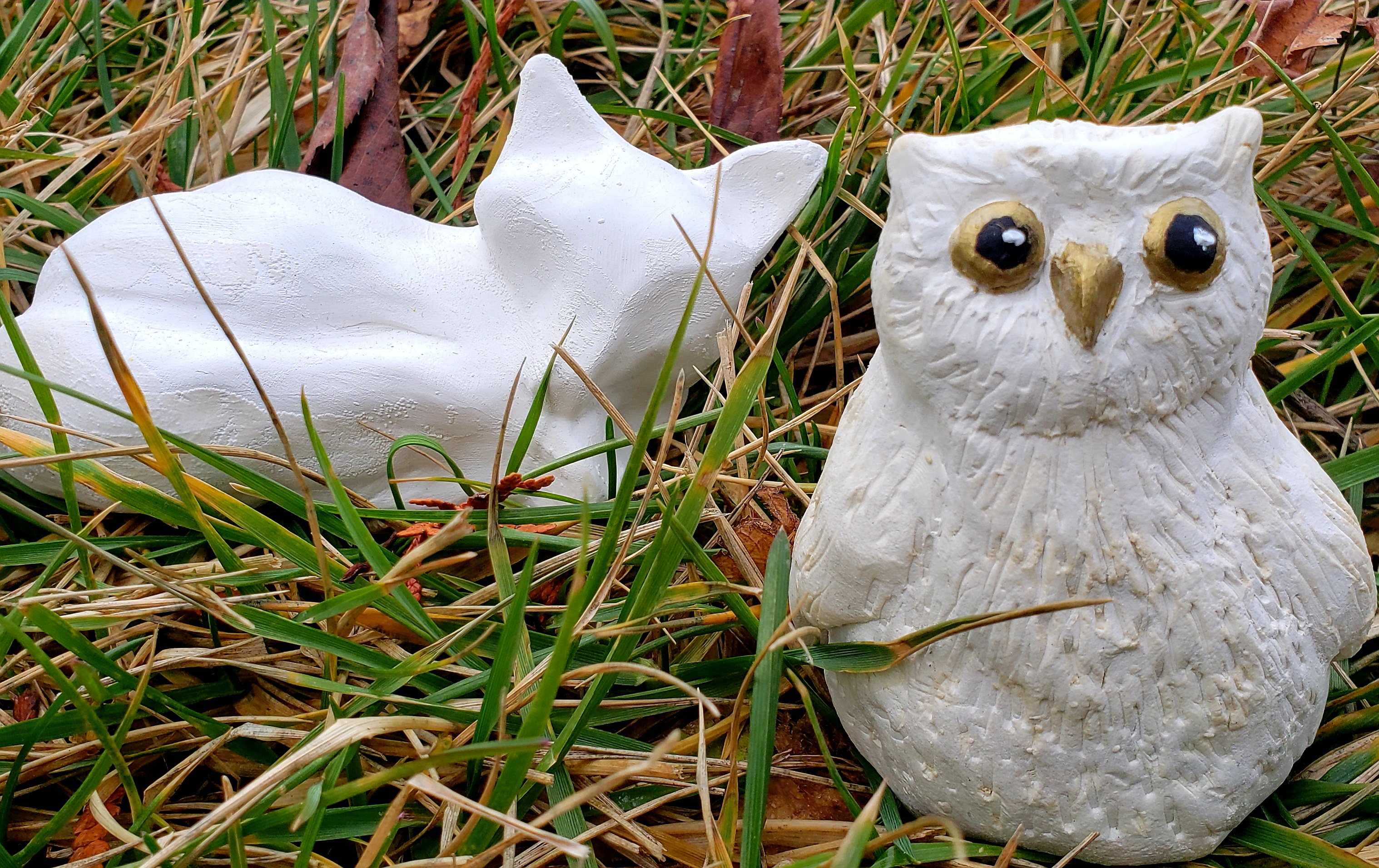 simple owl and fox made of clay sitting in the grass