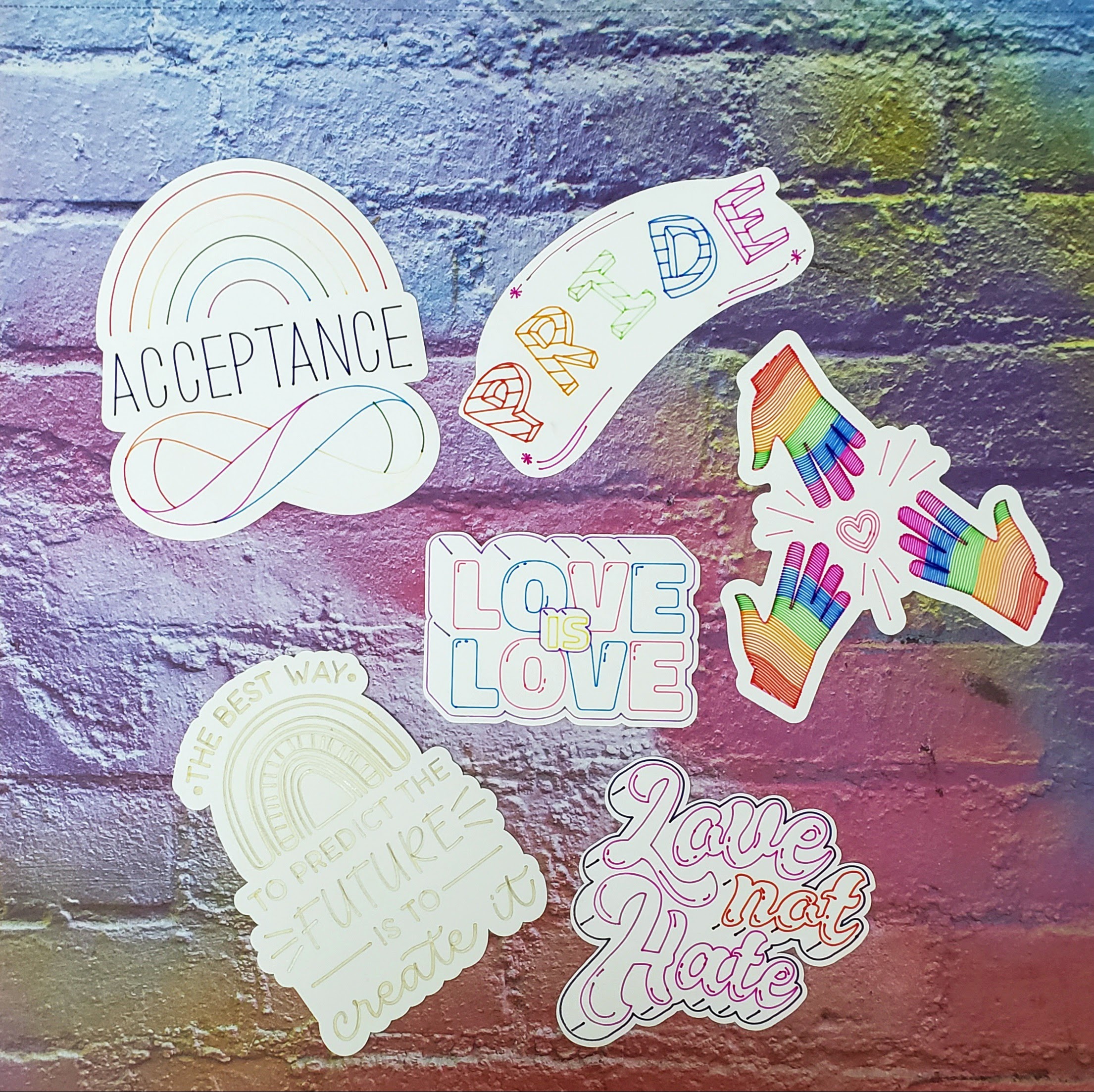 Pride stickers with sayings including "Acceptance" "Love is Love" "Love not Hate" and "The best way to predict the future is to create it"