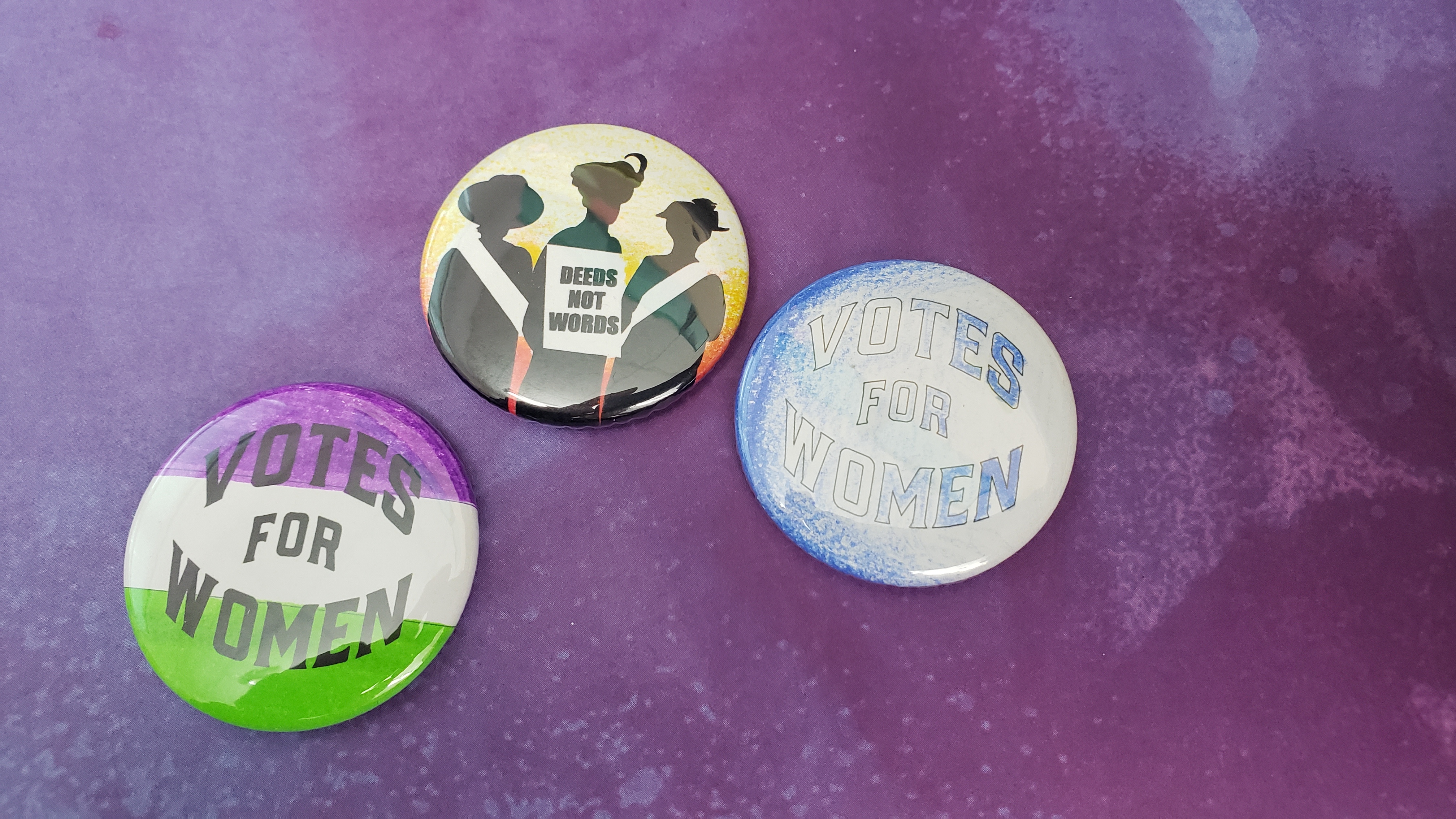 buttons with suffrage sayings "Votes for Women" and "Deeds not Words"