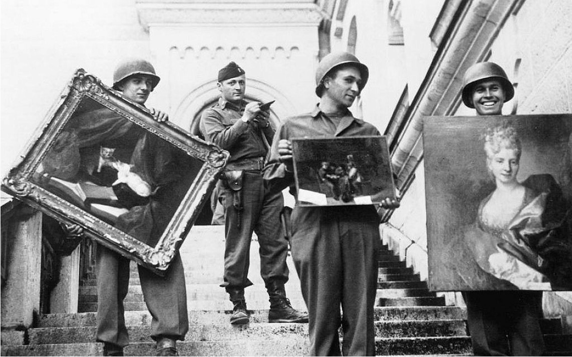 black and white photograph of soldiers carrying paintings