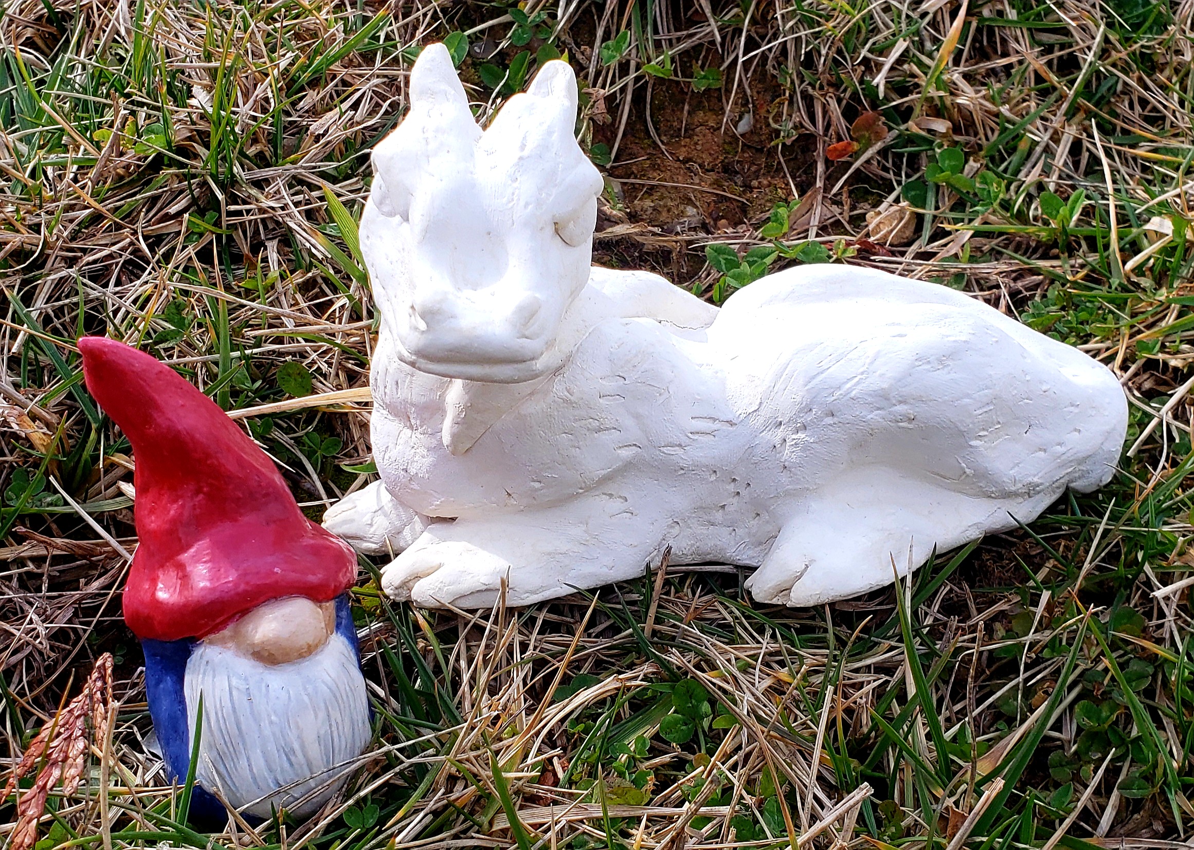 a clay gnome and dragon sitting in the grass