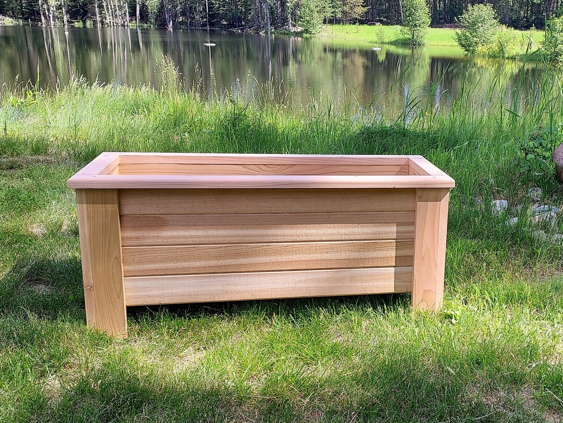 cedar planter box in grass in front of water