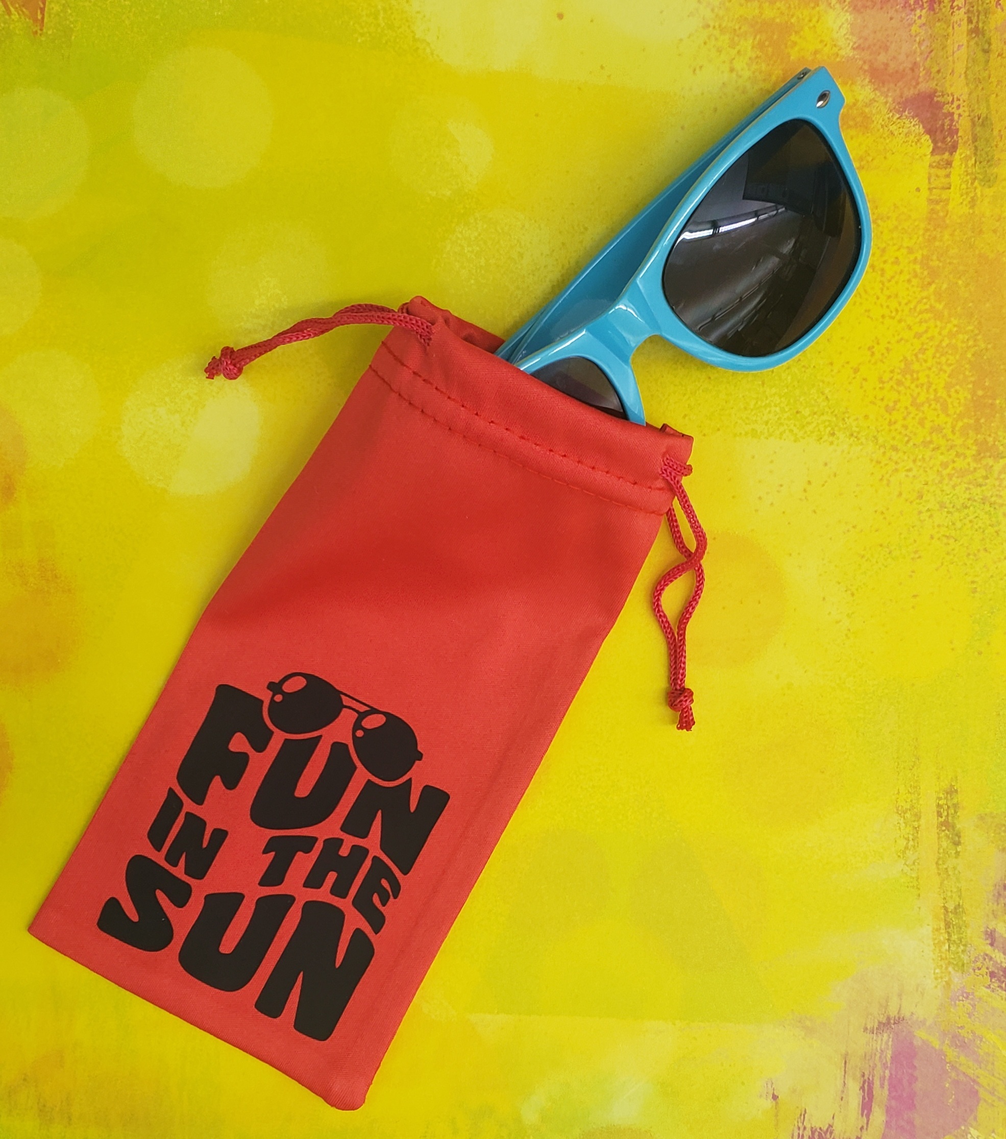 red sunglass case reading "Fun in the Sun" on a yellow background with blue sunglasses