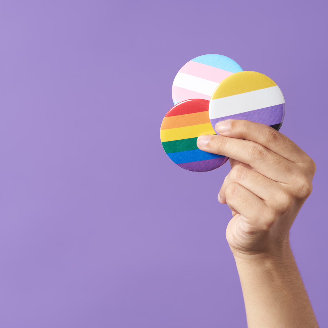 hand holding 3 lgbtq pride buttons