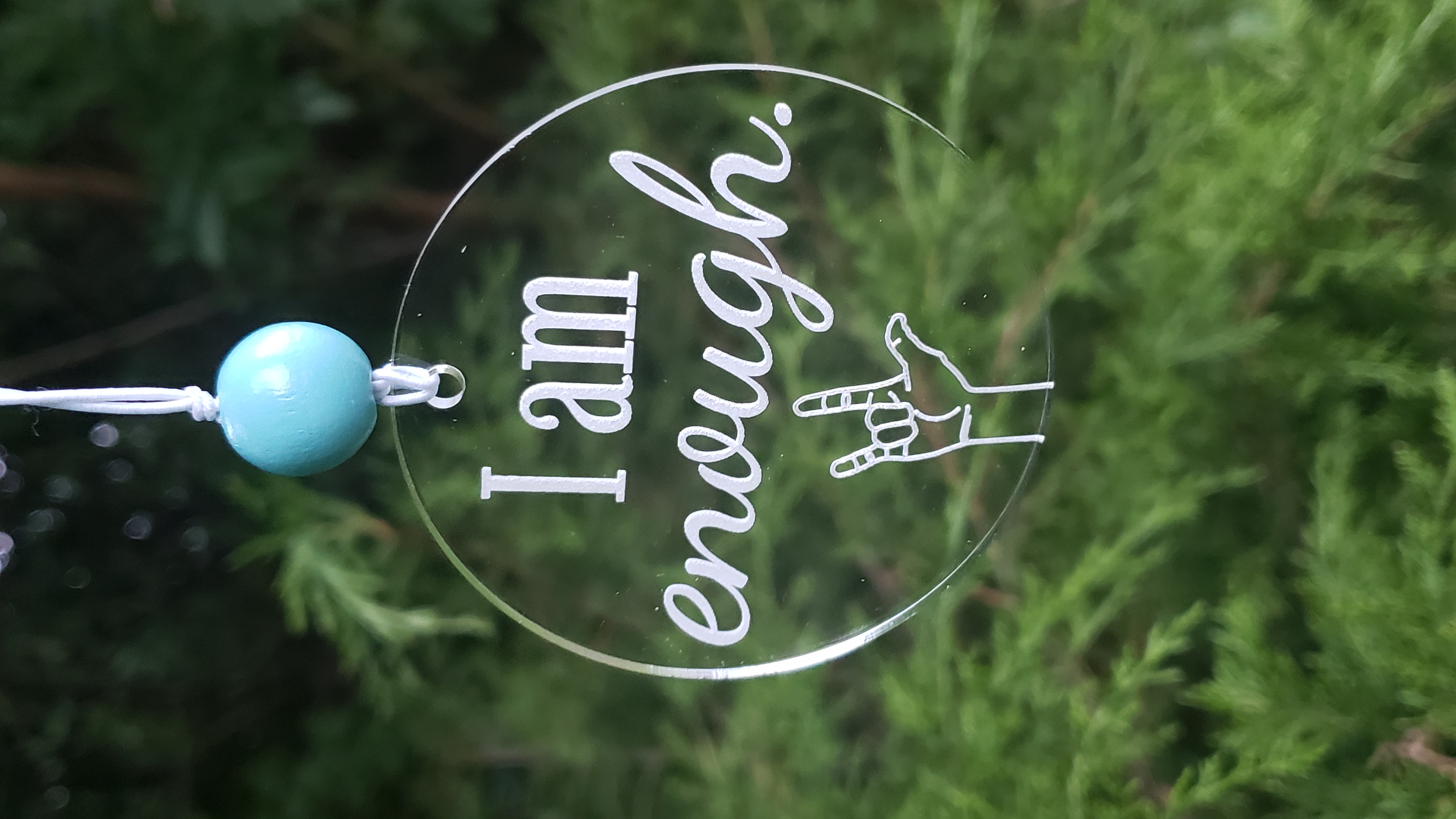 Circular engraved acrylic reading I am enough with the sign language symbol for 'I love you'