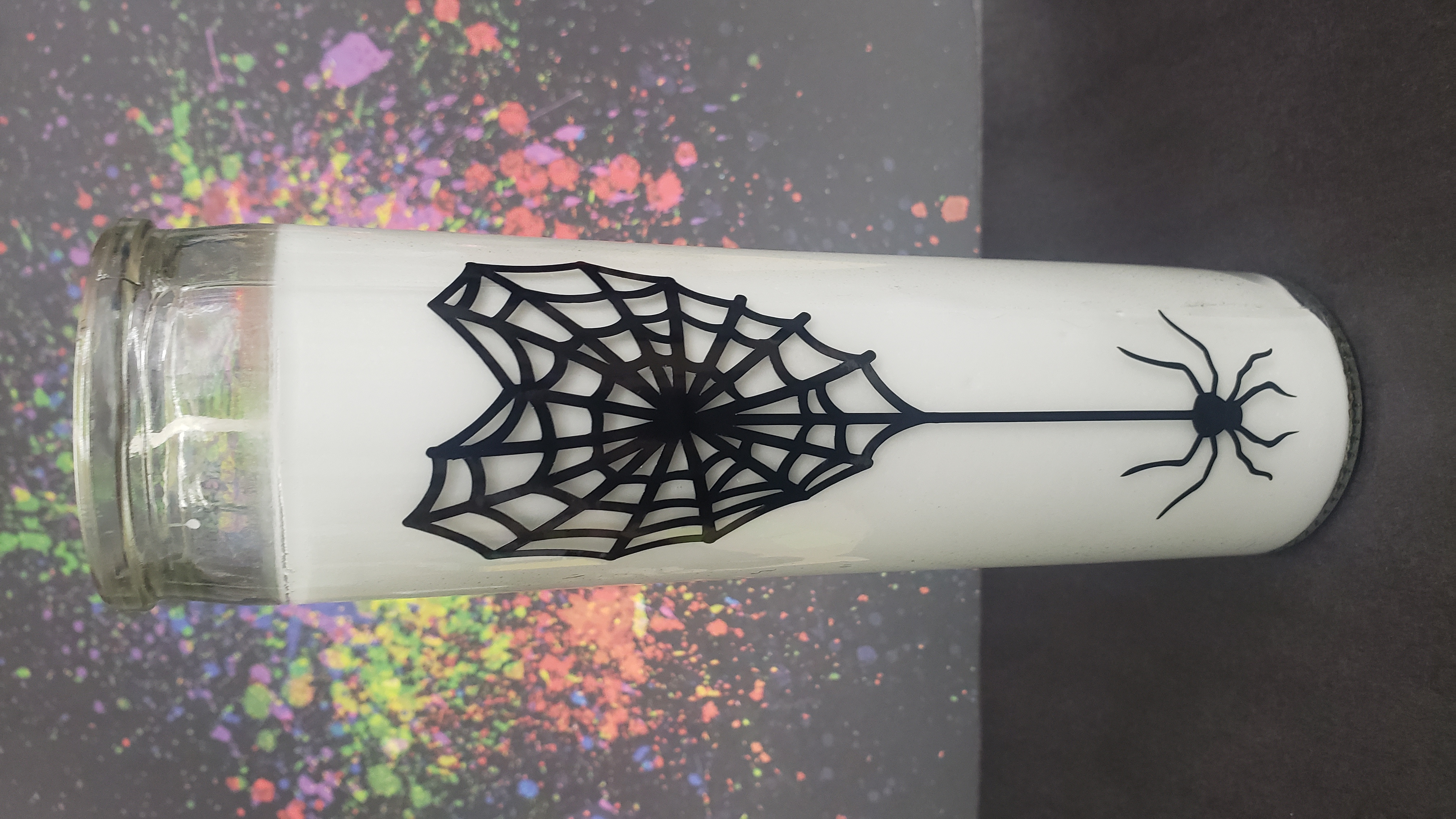 White candle with black spiderweb sticker
