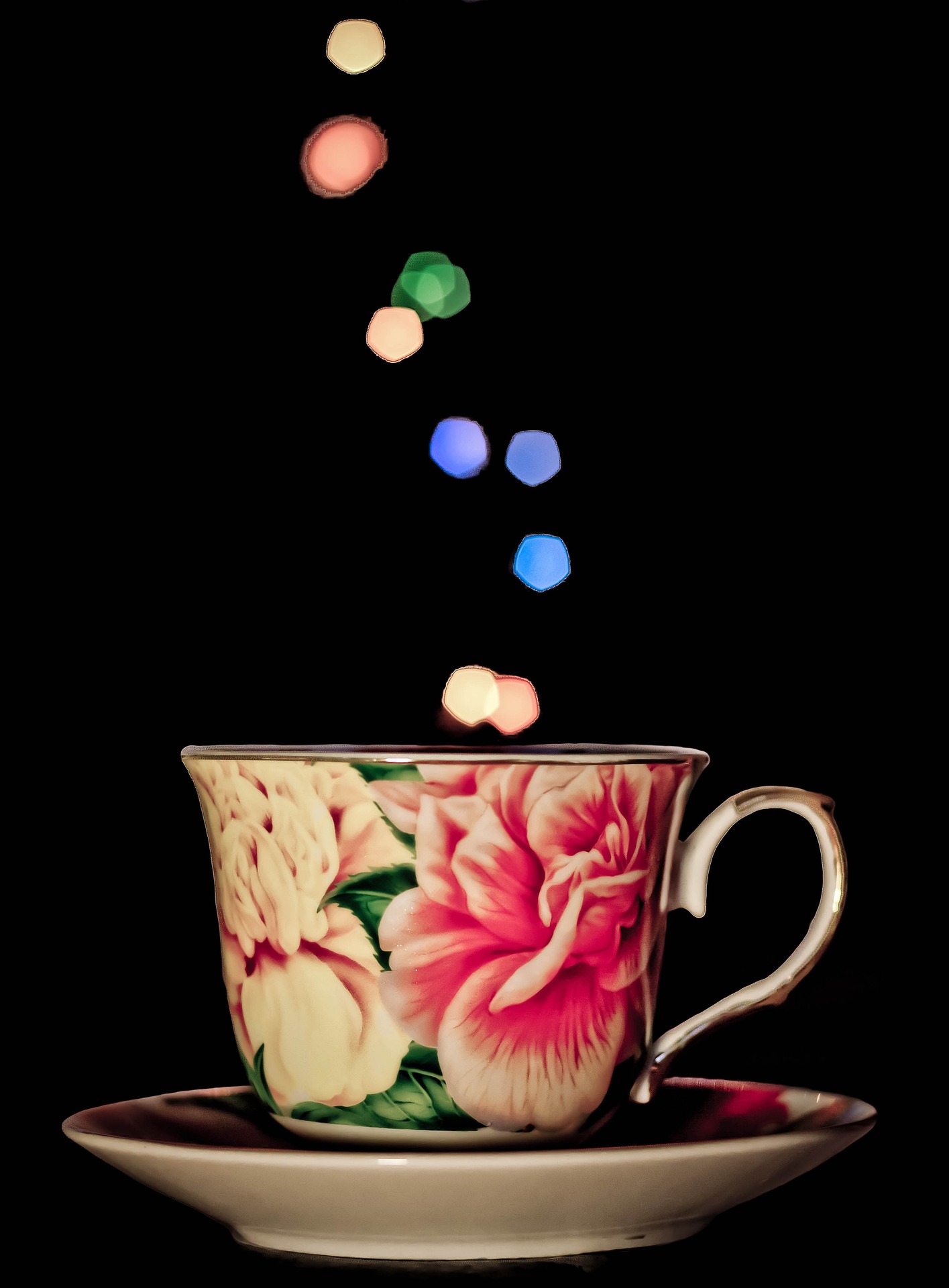 Cup and saucer with pink flower on cup. Small colorful shapes are emanating from the cup.