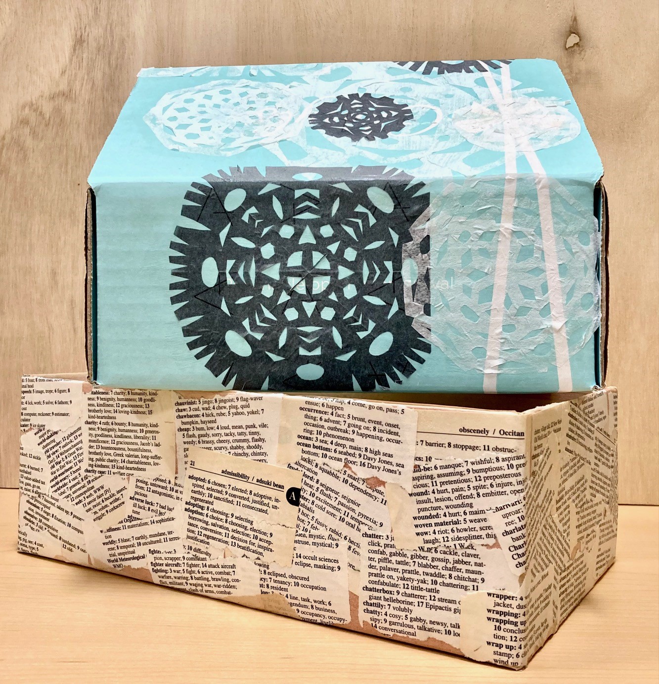 a stack of two cardboard shoeboxes decorated with paper cutouts