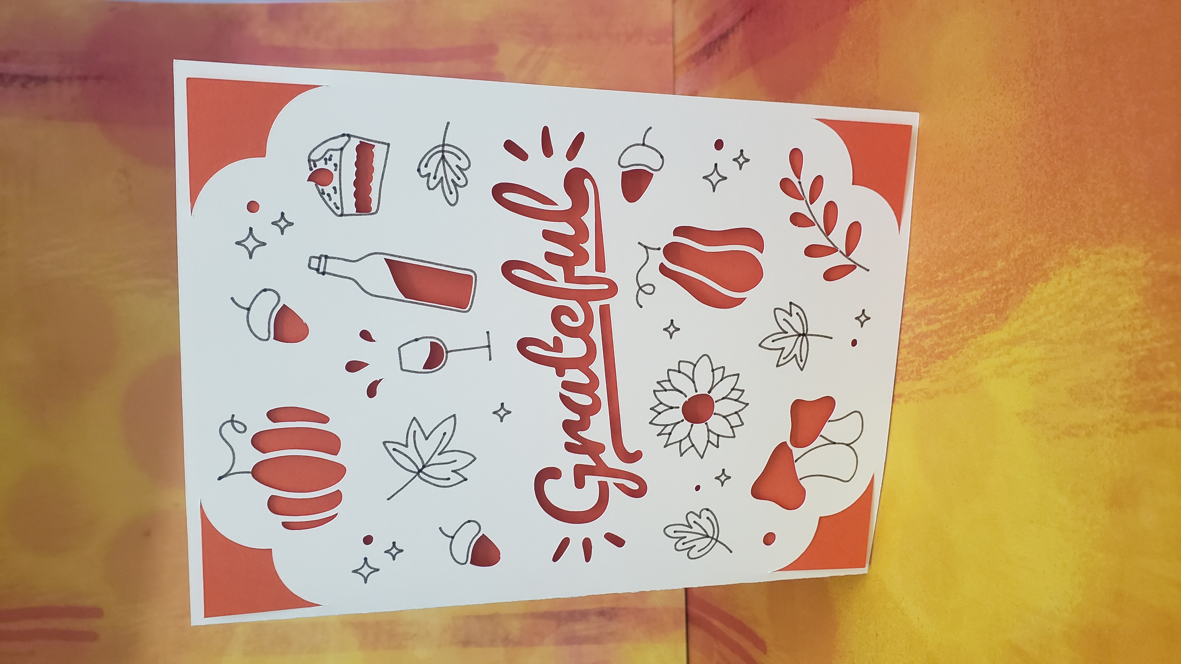 Orange and tan card reads "grateful" with fall decorations - pumpkins, pie, and flowers.