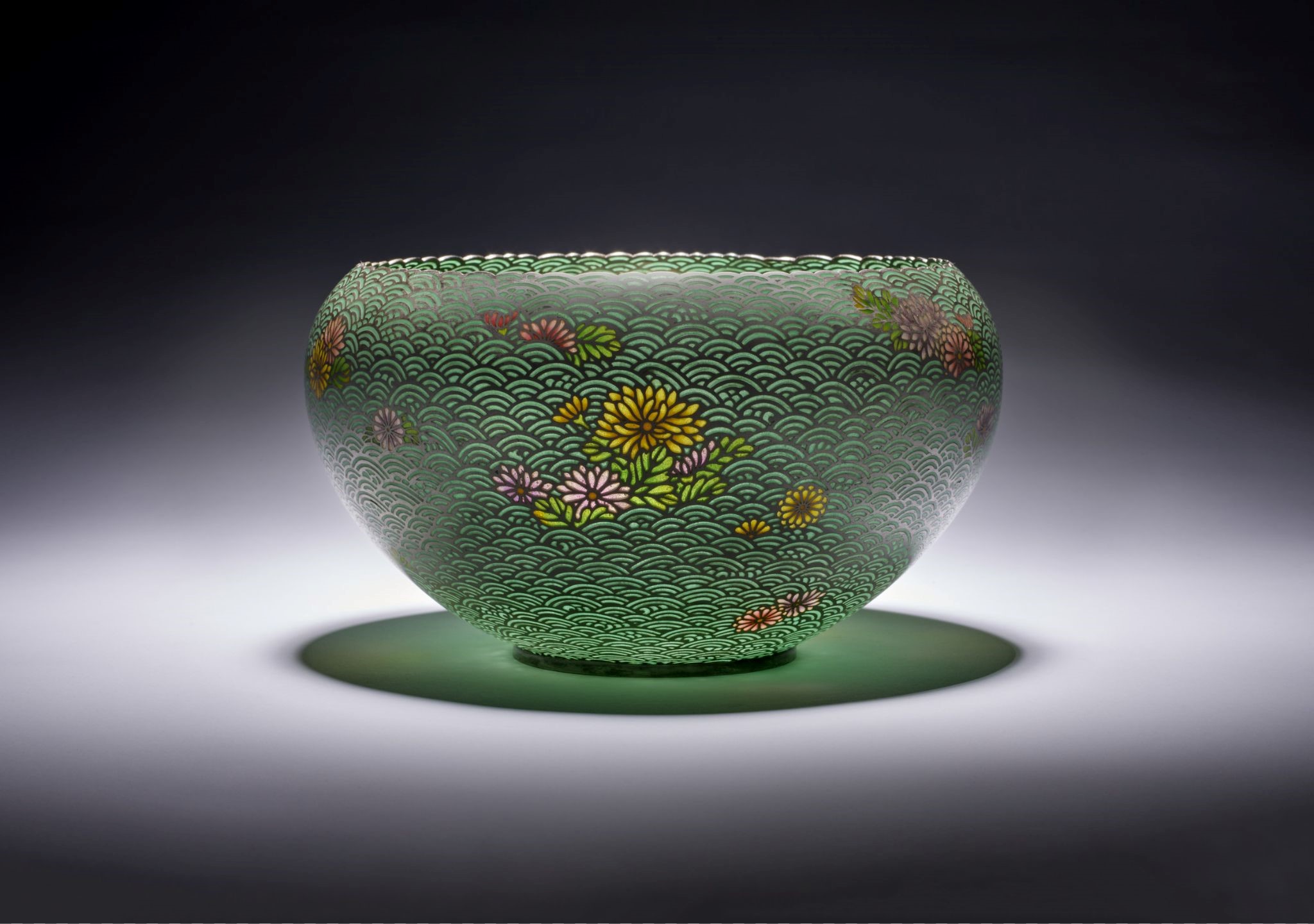 a green porcelain bowl with delicate spirals and yellow flowers