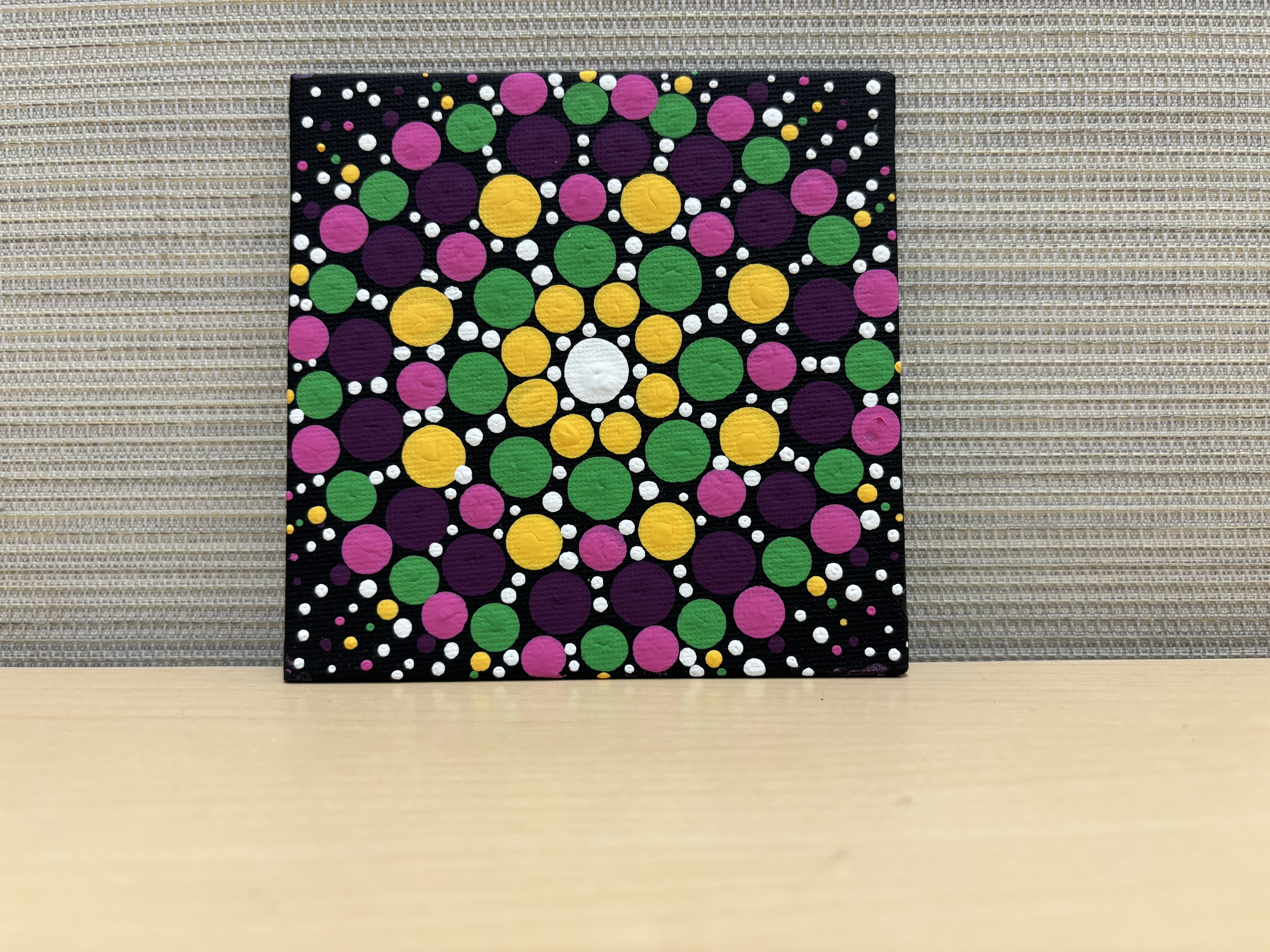 Mandala dot painting on small black canvas.