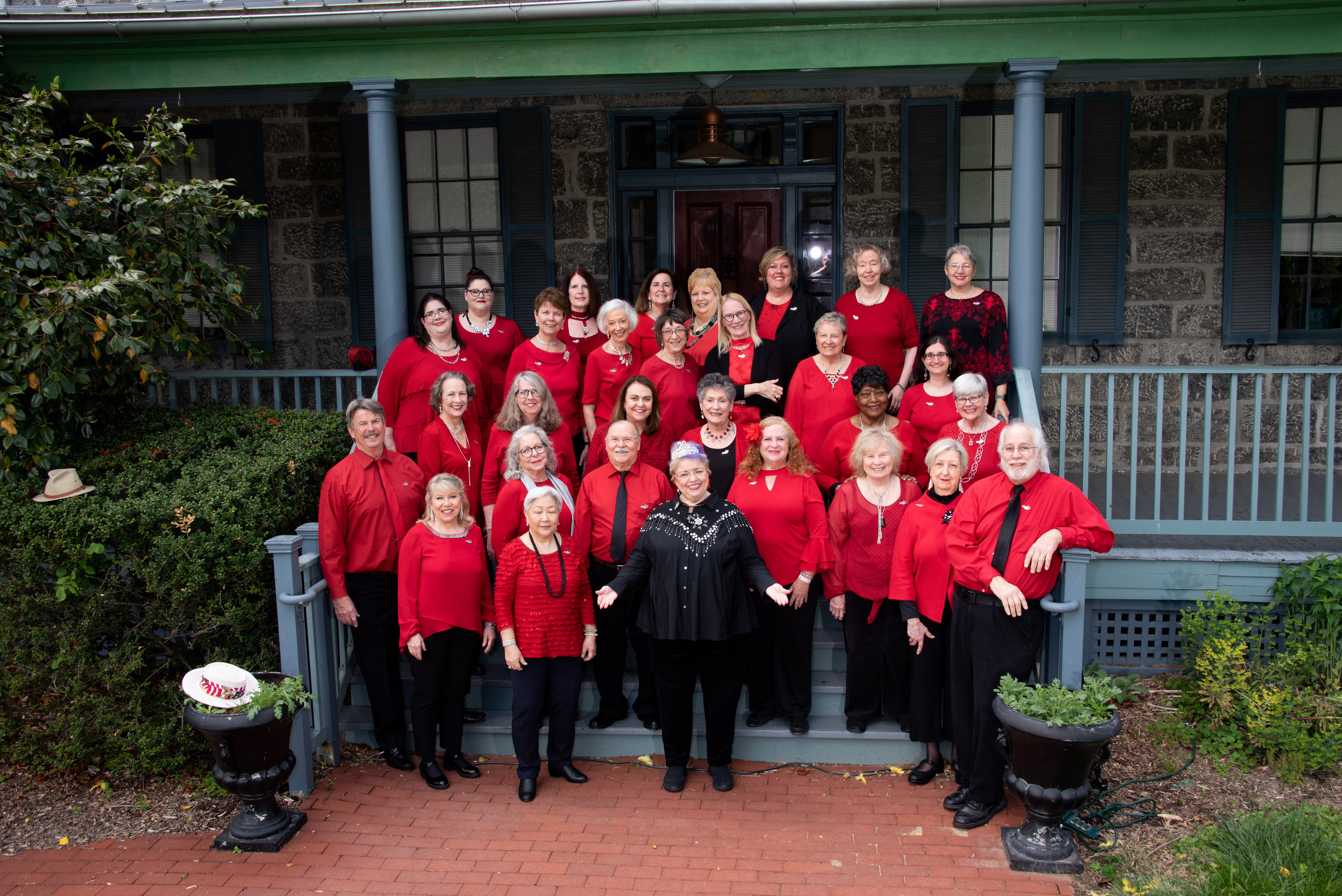 ShowTime Singers standing on a house porch all dressed in red and black
