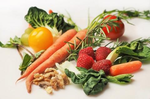 pile of fresh veggies including carrots, raspberries, herbs, nuts, and tomatoes 