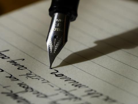 an nib of an ink pen is shown writing words on a ruled page