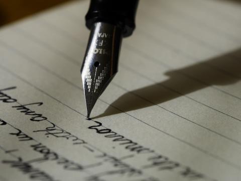 cursive writing on lined paper and a nib of a fountain pen