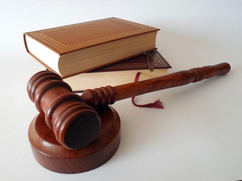 a wooden judges hammer and a pile of leather bound law books