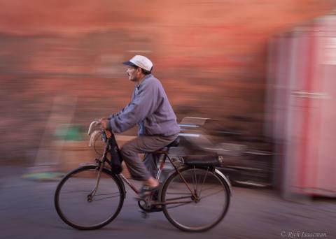 a man riding a bike wearing loose arabic pajamas and shirt