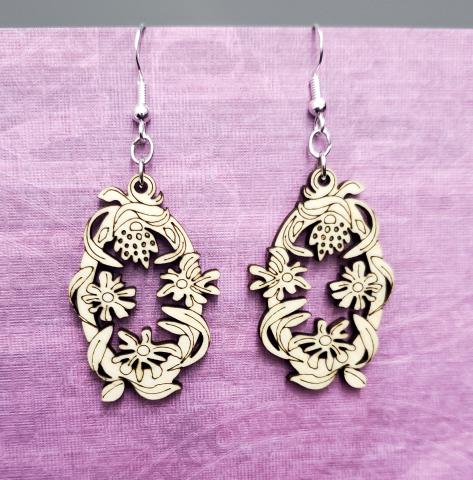 Laser cut wooden floral earrings on a purple textured background