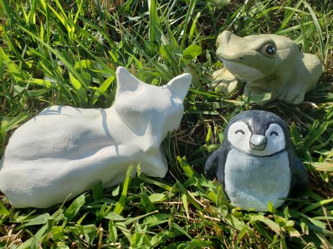 a fox frog and penguin made of air dry clay sitting in the grass